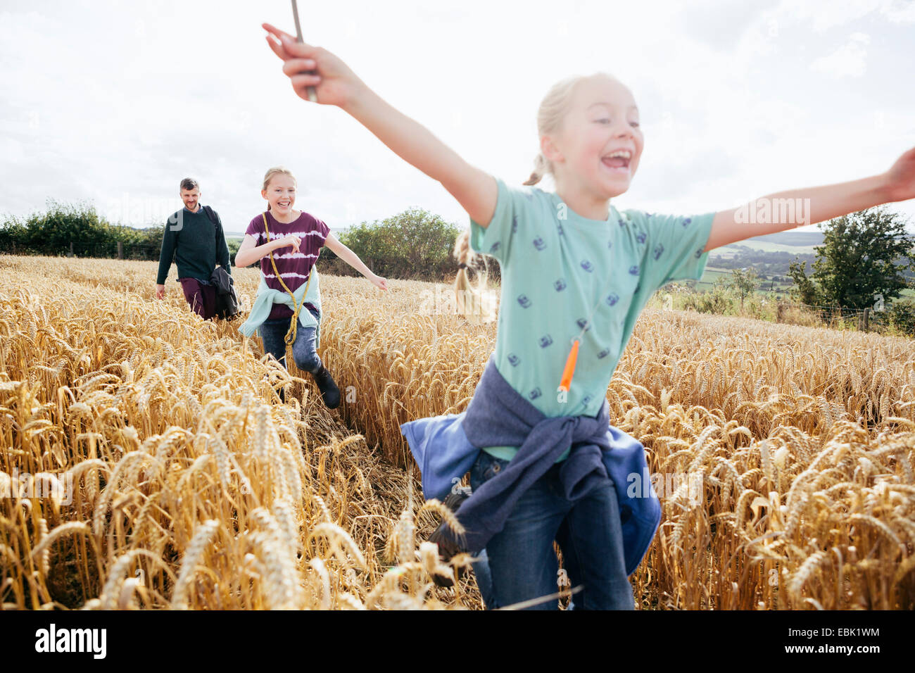 Girl running through field with arms out Stock Photo