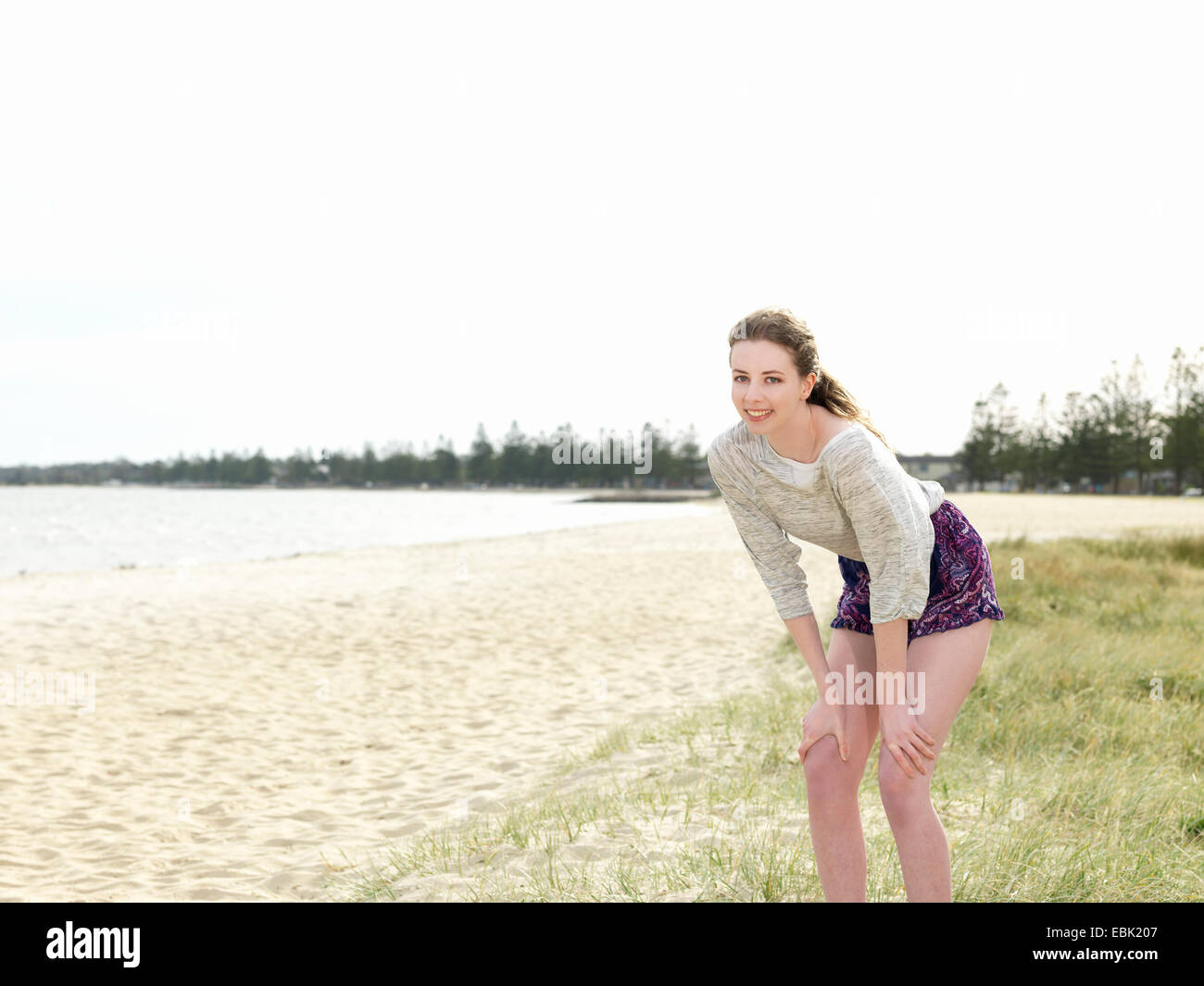 Young woman bending forwards with hands in knees Stock Photo