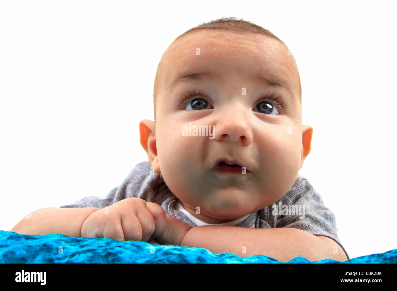 baby lying in a bed on the belly looking up Stock Photo Alamy