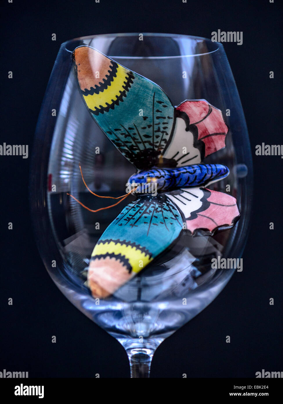 Studio macro image, beautiful ceramic butterfly in a clear wine glass with black background Stock Photo
