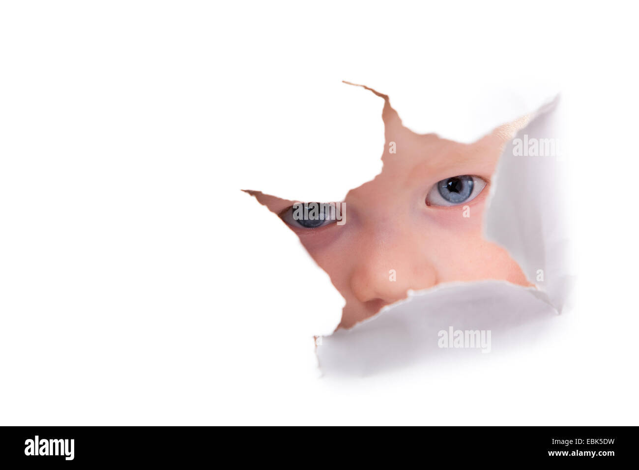 little boy looking through hole in a white paper surface Stock Photo