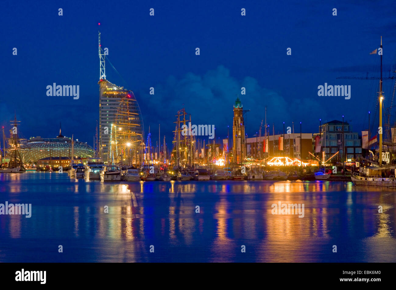 tall ships in harbour at night, lighthouse, hotel Atlantic and Klimahaus in background, Germany, Bremerhaven Stock Photo