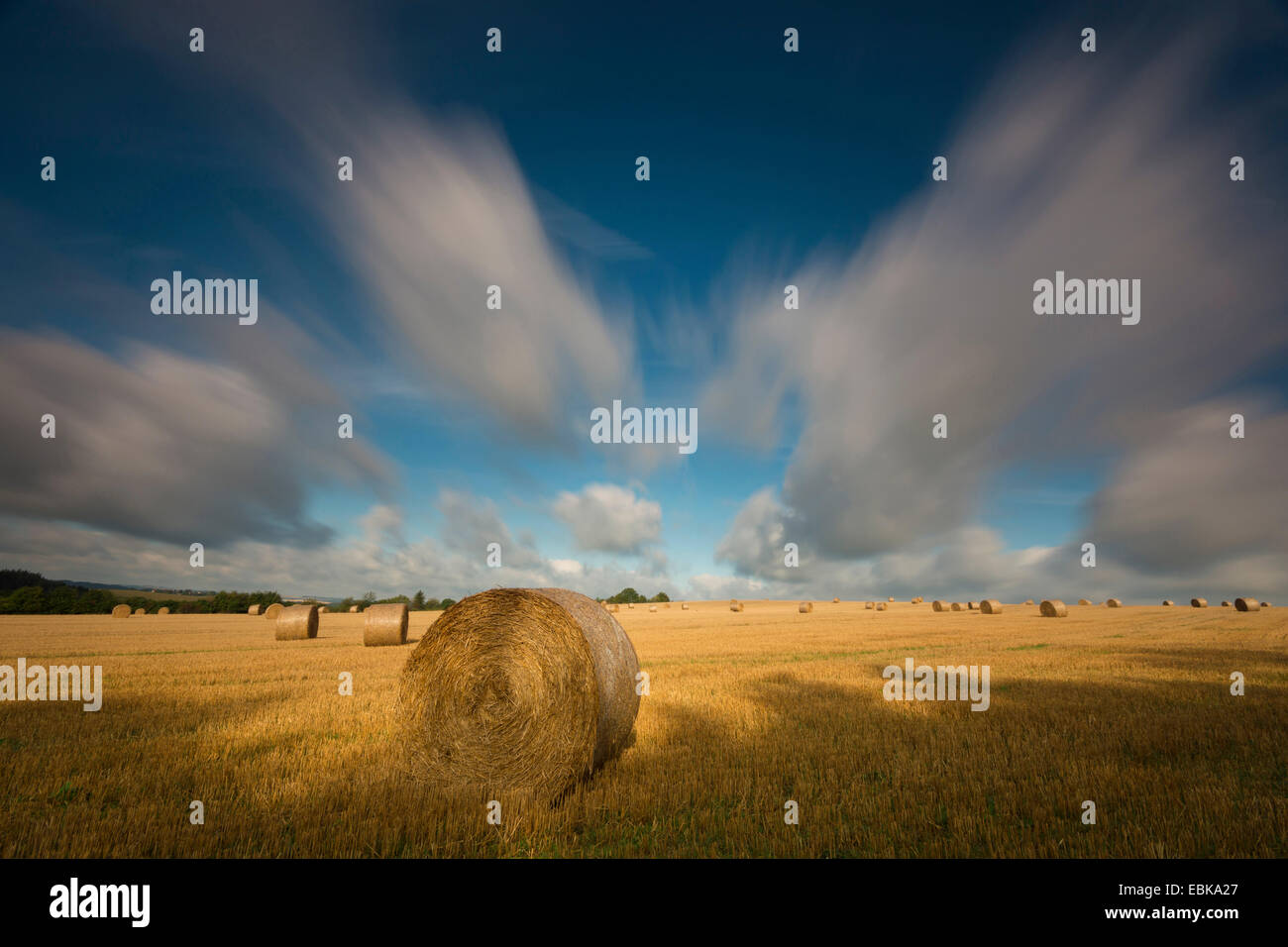 moving clouds over a stubble field with bales of straw, longtime exposure, Germany, Saxony, Vogtlaendische Schweiz Stock Photo