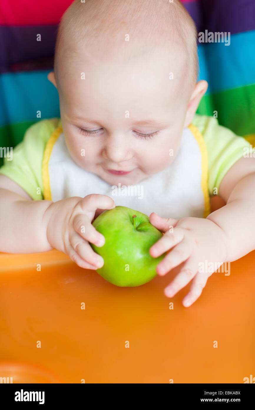 Adorable baby eating in high chair. Baby's first solid food Stock Photo