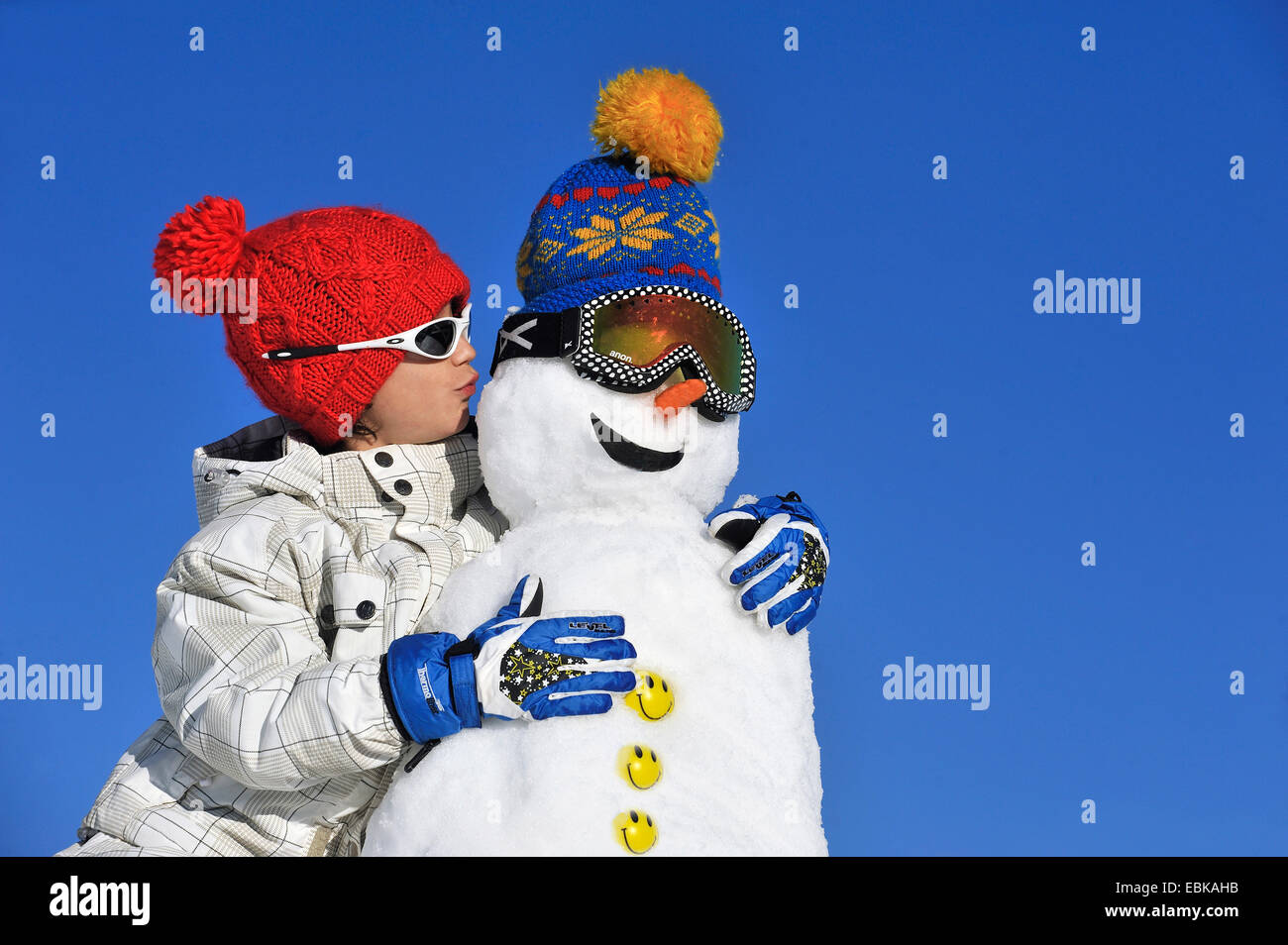 boy pecking a snow man on the cheek, France Stock Photo