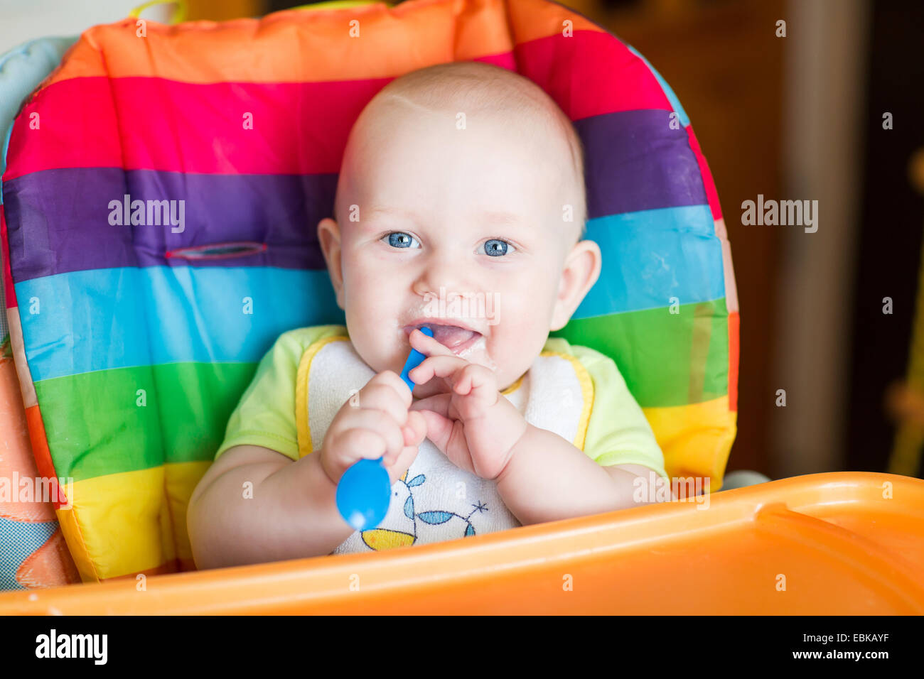Adorable baby eating in high chair. Baby's first solid food Stock Photo