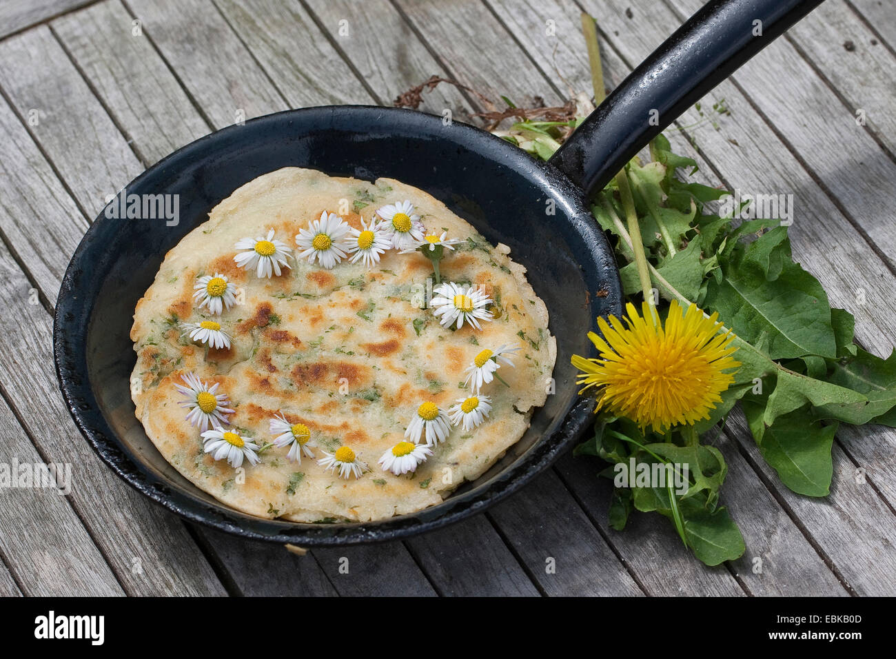 pancake with daisies and dandelion in a cast-iron pan, Germany Stock Photo
