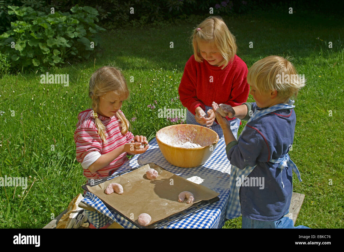 children baking dread fruit bread rolls out of bread dough and raspberries, Germany Stock Photo