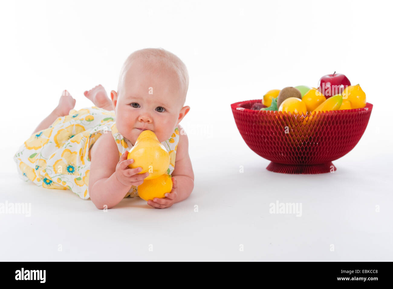 10 months old baby with fruit basket and fruits in its hands Stock