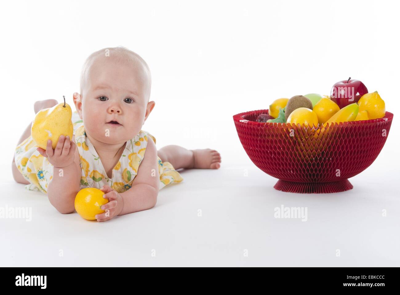 10 months old baby with fruit basket and fruits in its hands Stock