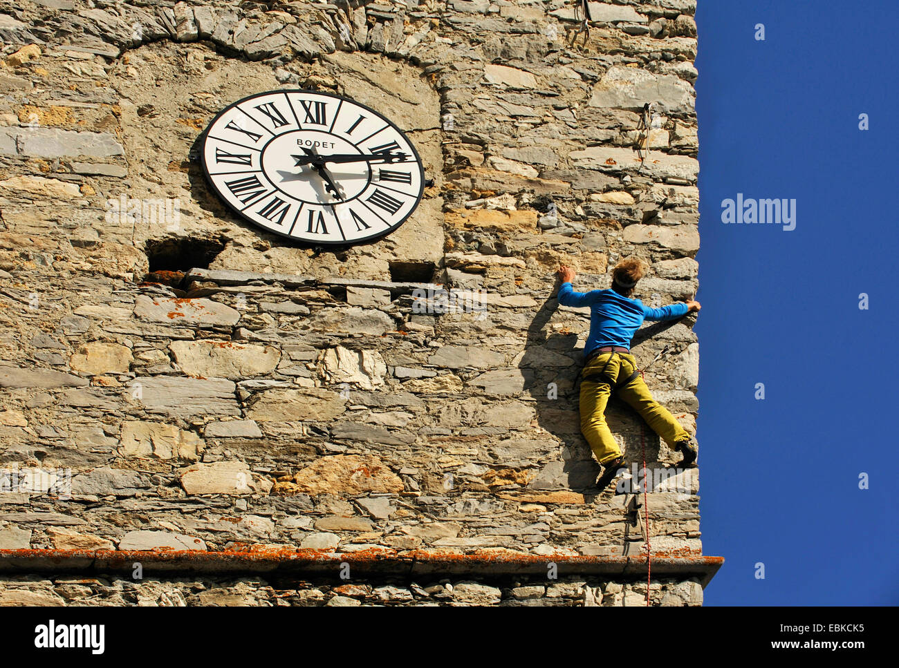 climber climbing next to church clock, France, Savoie Stock Photo