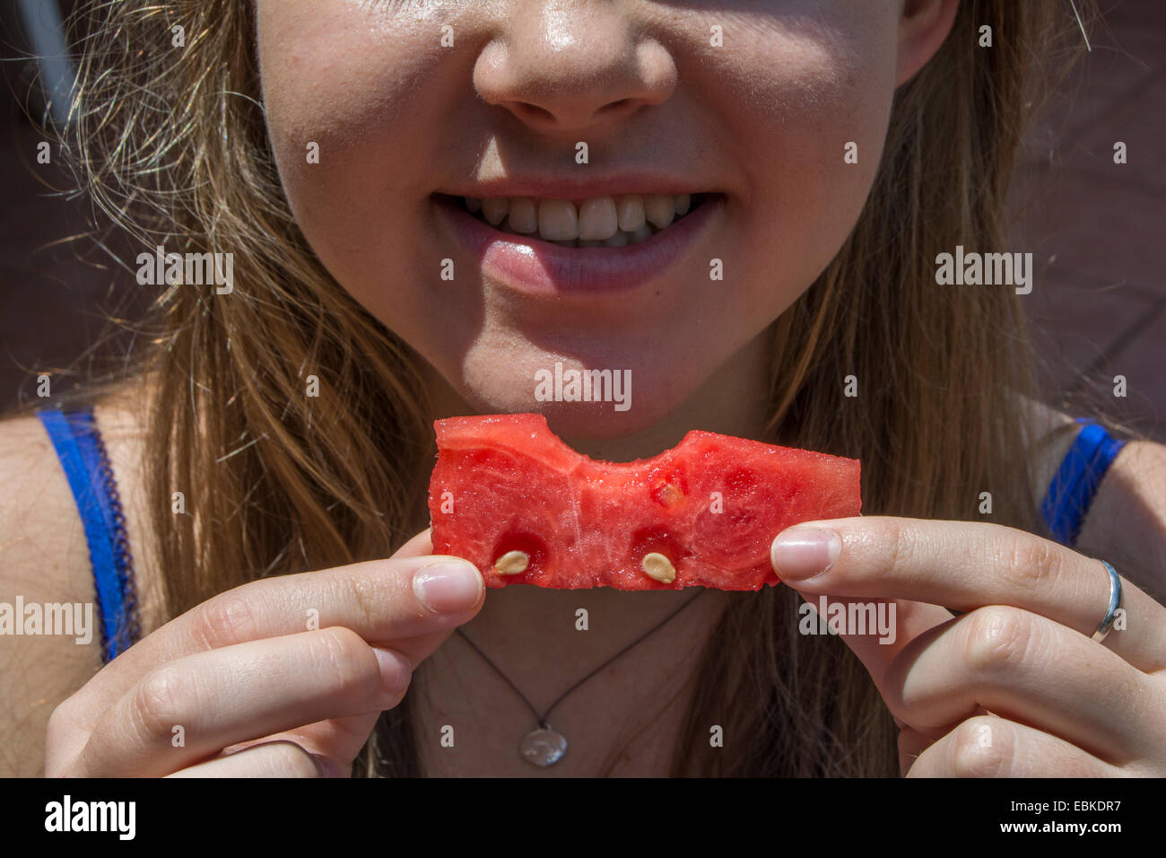 A girl holding a piece of watermelon with a bite out of it Stock Photo