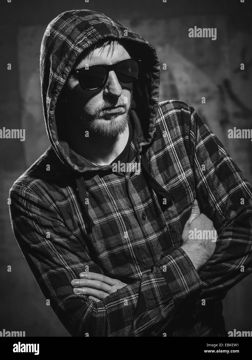 Handsome young man wearing  a checked shirt and a sunglasses, concrete wall on background - black and white image Stock Photo