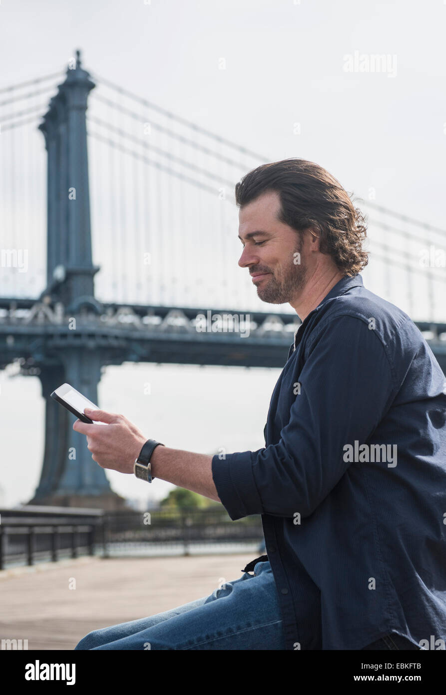 USA, New York State, New York City, Brooklyn, Man using tablet pc, Manhattan Bridge in background Stock Photo