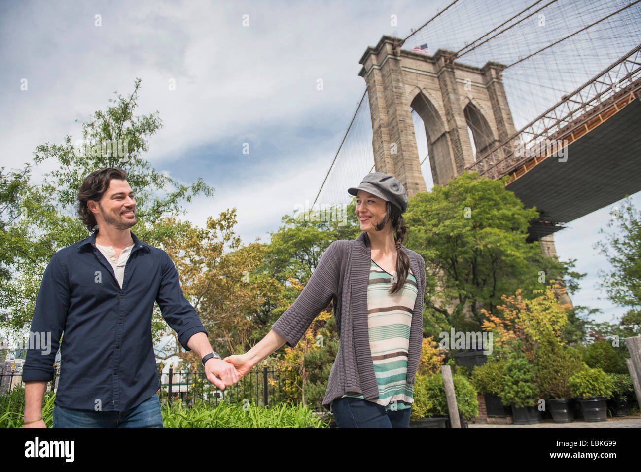 Happy couple holding hands and walking with Brooklyn Bridge in background Stock Photo