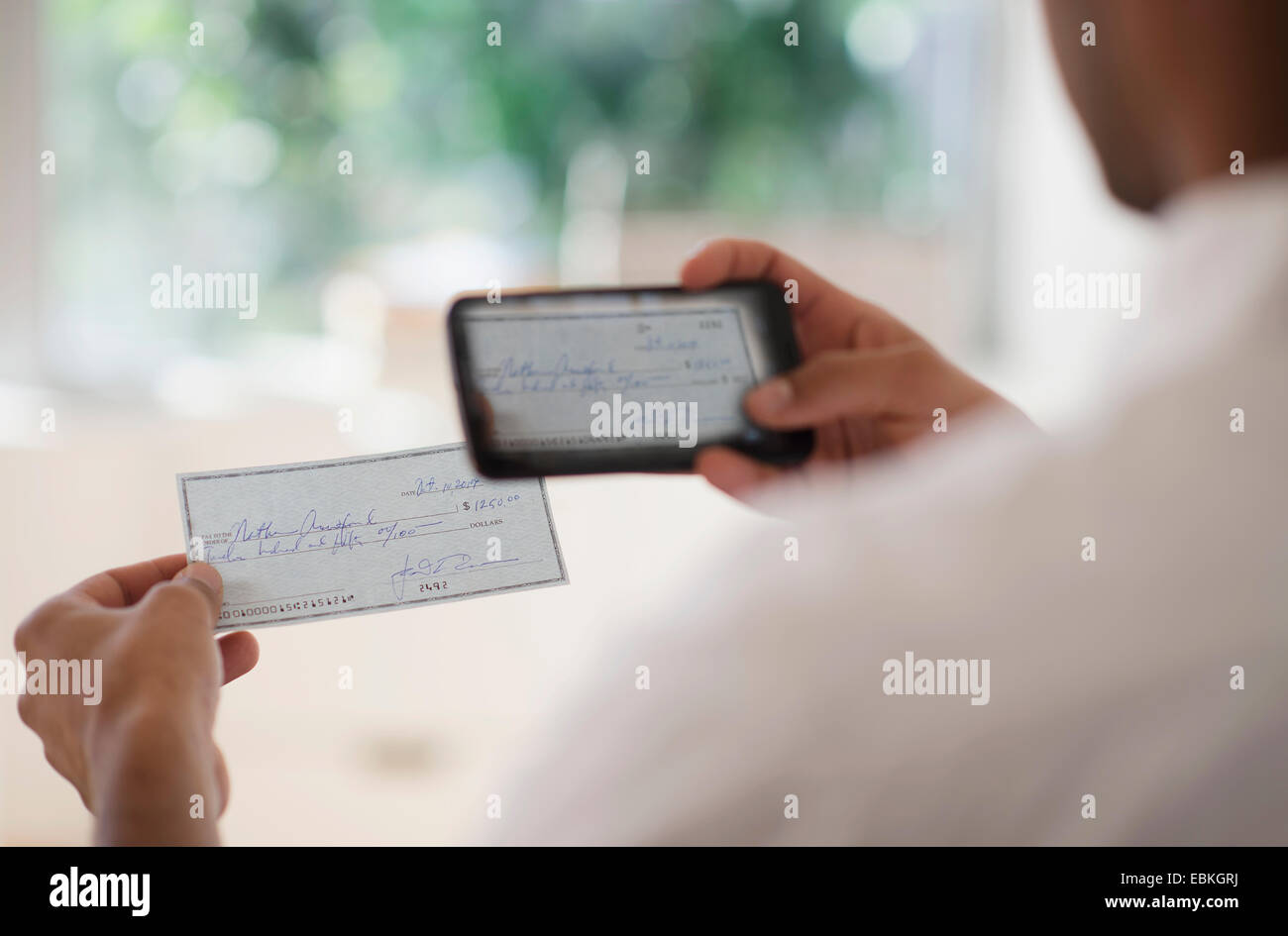 Man taking photo of banking check with cell phone Stock Photo