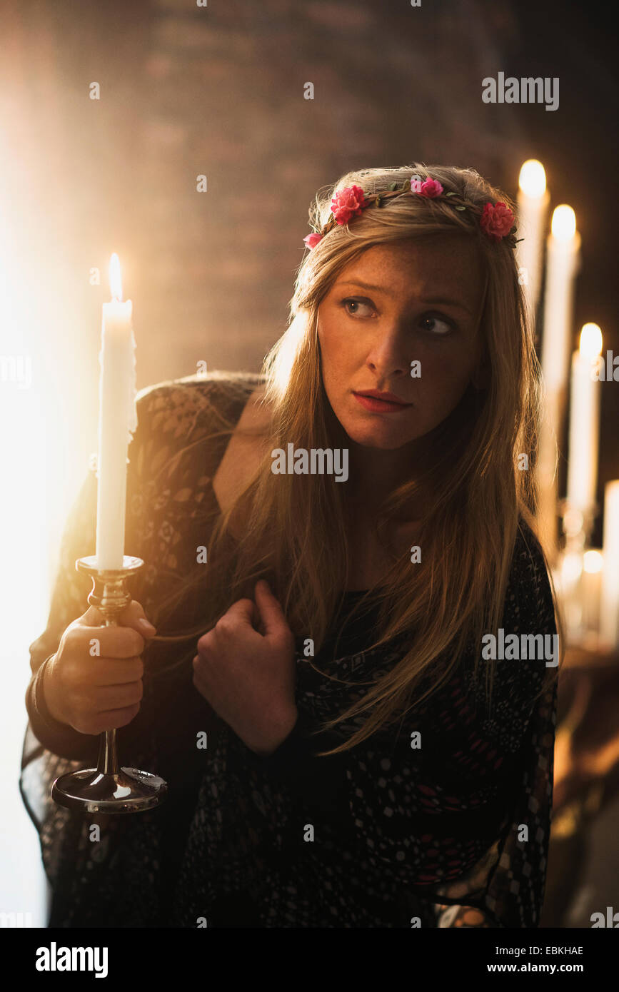 Sorceress holding candle in dark room Stock Photo