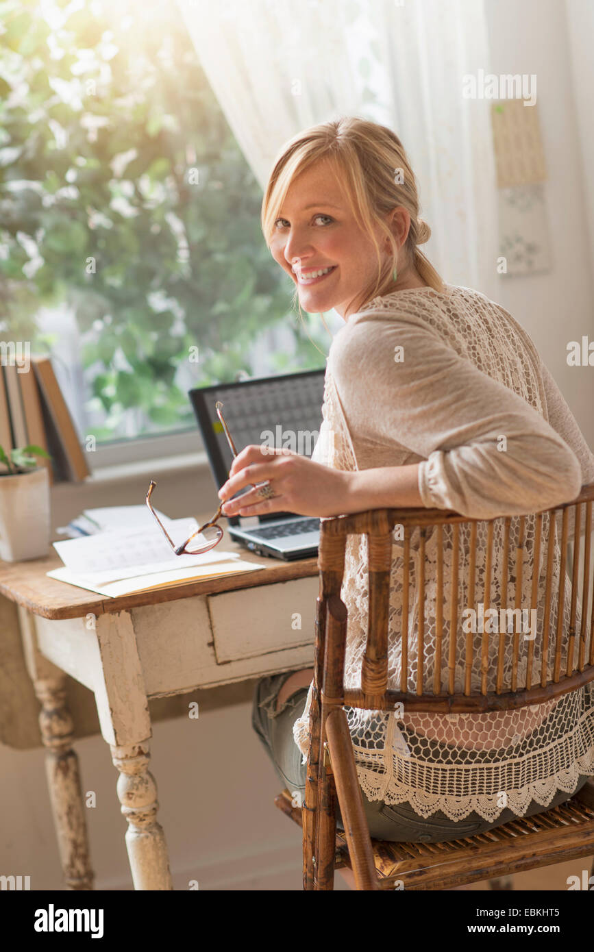 Smiling woman sitting at desk and looking over shoulder Stock Photo