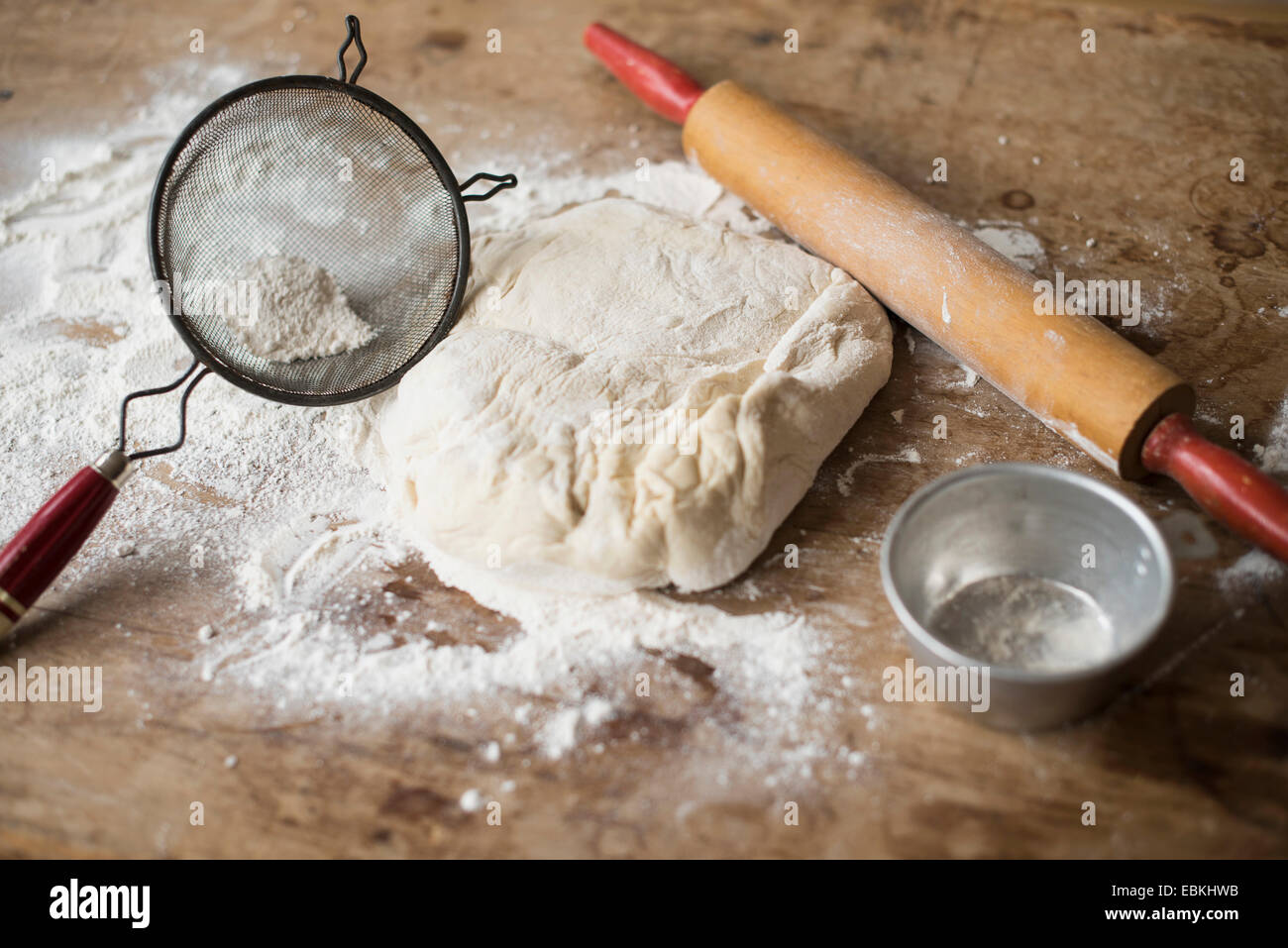 Rolling pin, Strainer and dough on kitchen counter Stock Photo