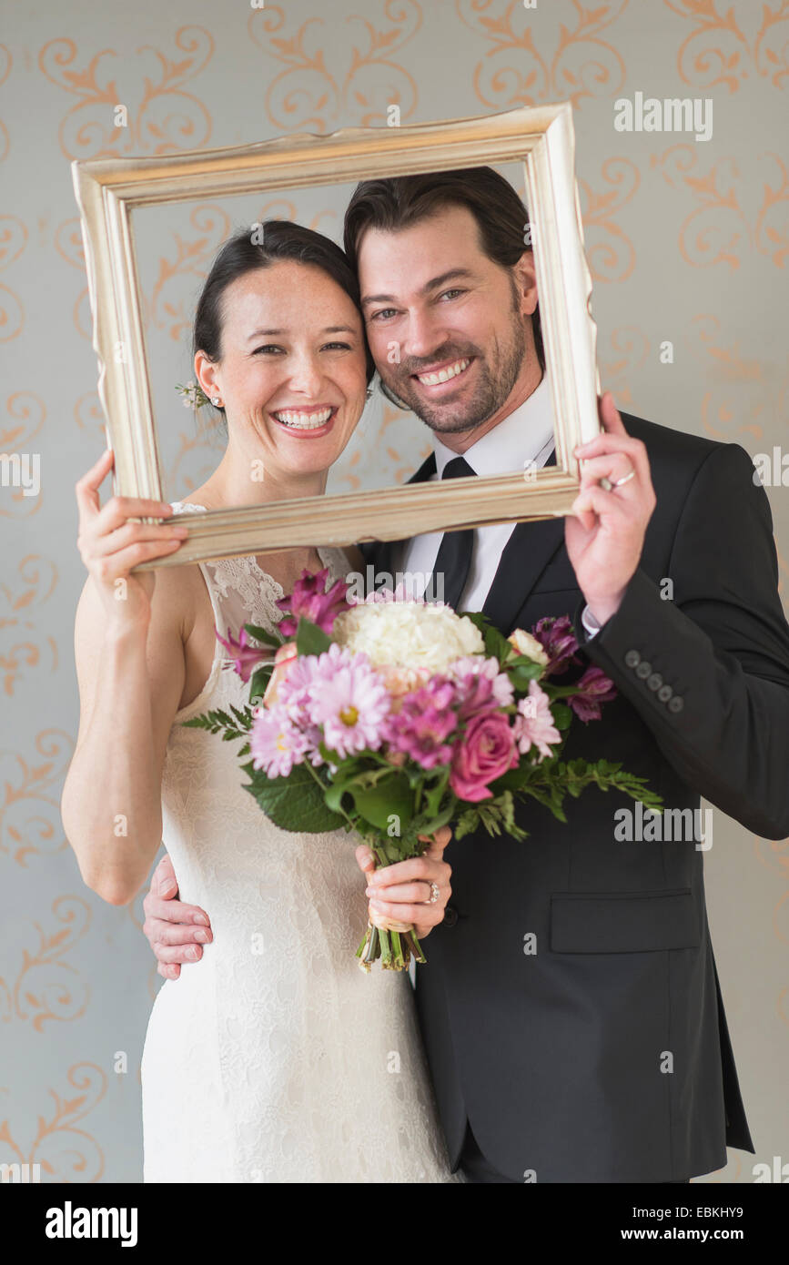 Bride and groom posing with picture frame Stock Photo