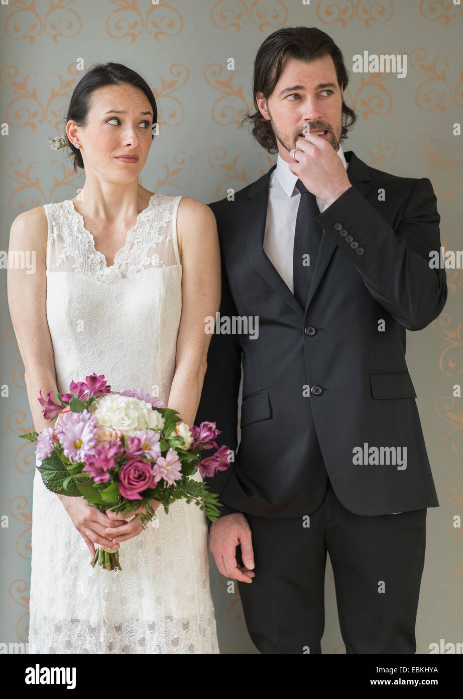 Anxious bride and groom posing with bunch of flowers Stock Photo