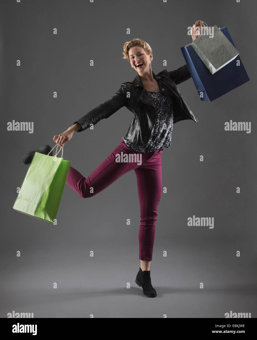 Studio shot of cheerful woman holding shopping bags Stock Photo