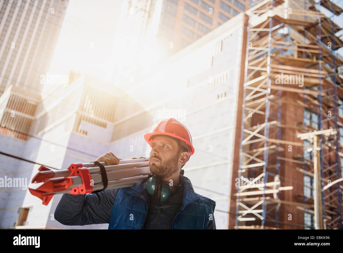 Construction worker carrying tripod on shoulder Stock Photo Alamy