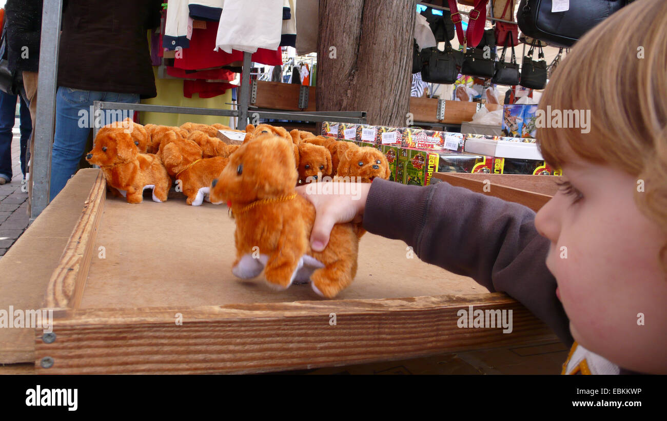 small boy playing with a soft toy dog at an open market, Spain, Balearen, Majorca, Alcudia Stock Photo