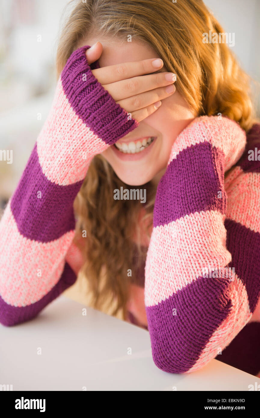 Girl (12-13) grinning and covering eyes Stock Photo