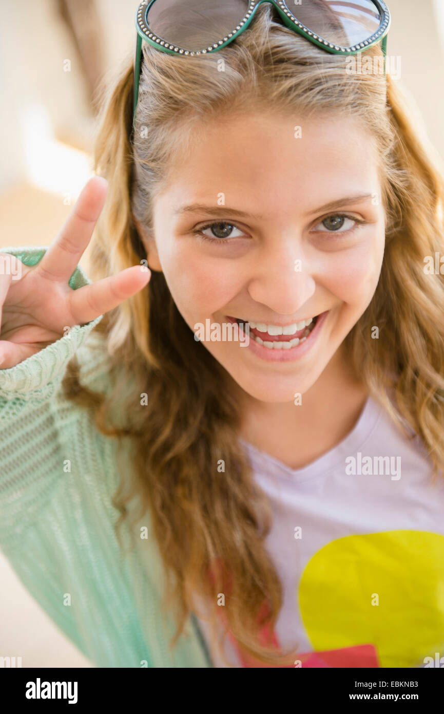 Portrait of smiling teenage girl (12-13) showing peace sign Stock Photo