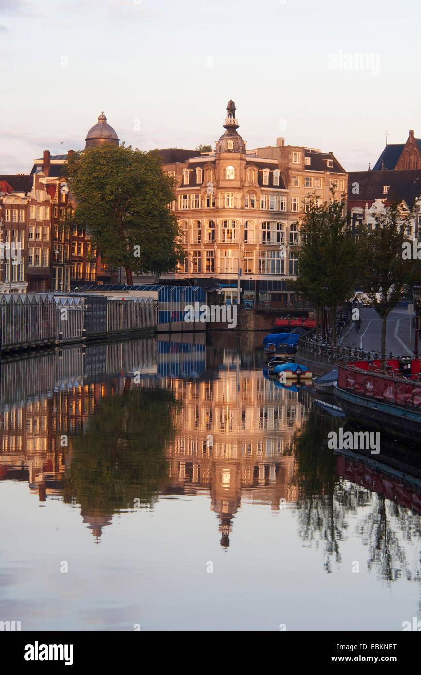 Reflections of historic buildings along Canal Singel in Amsterdam during golden hour, Netherlands, Europe Stock Photo