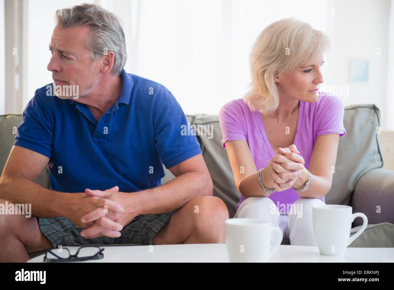 Portrait of couple sitting on sofa, looking away from each other Stock Photo
