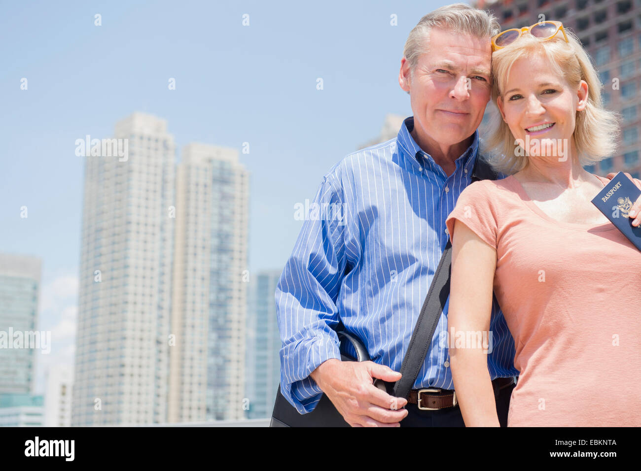 USA, New Jersey, Portrait of couple with passport against skyscrapers Stock Photo