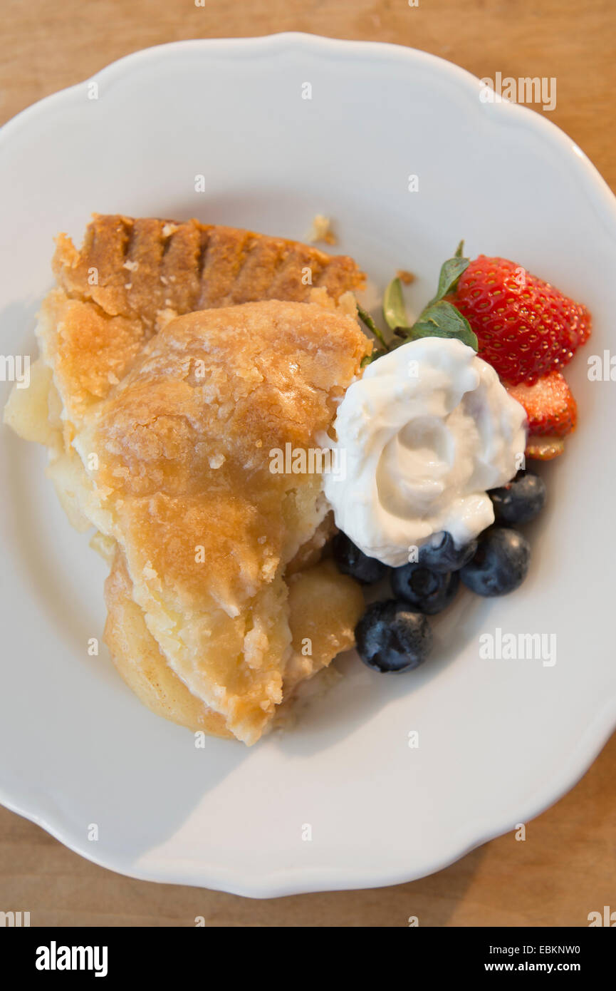 Close-up shot of portion of apple pie with fresh berries and cream on white plate Stock Photo