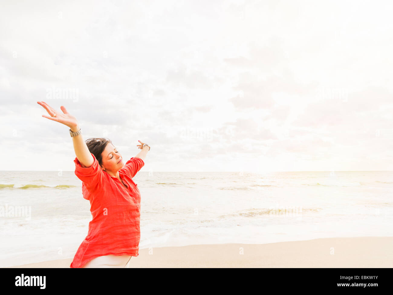 USA, Florida, Jupiter, Side view of woman standing with arms up on beach Stock Photo