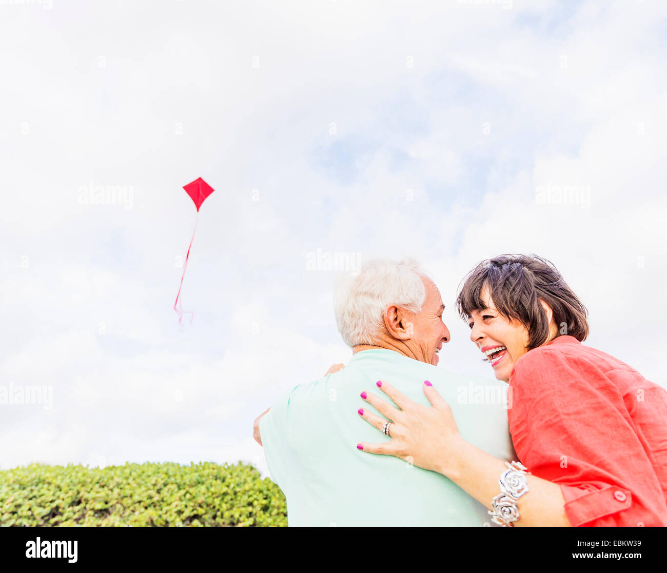 Low-angle view of couple flying kite together Stock Photo