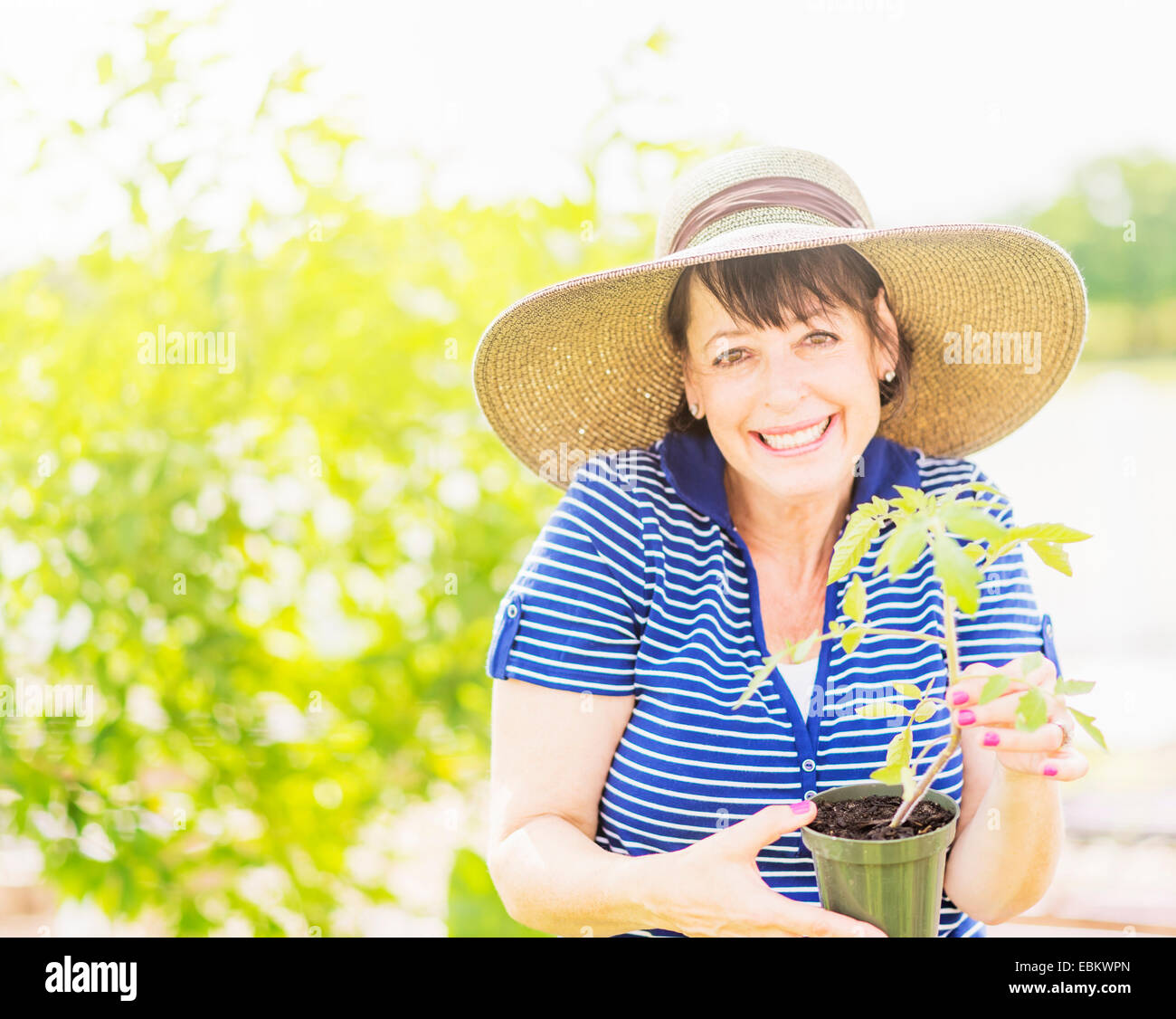 Portrait of smiling woman holding potted plant in garden Stock Photo ...