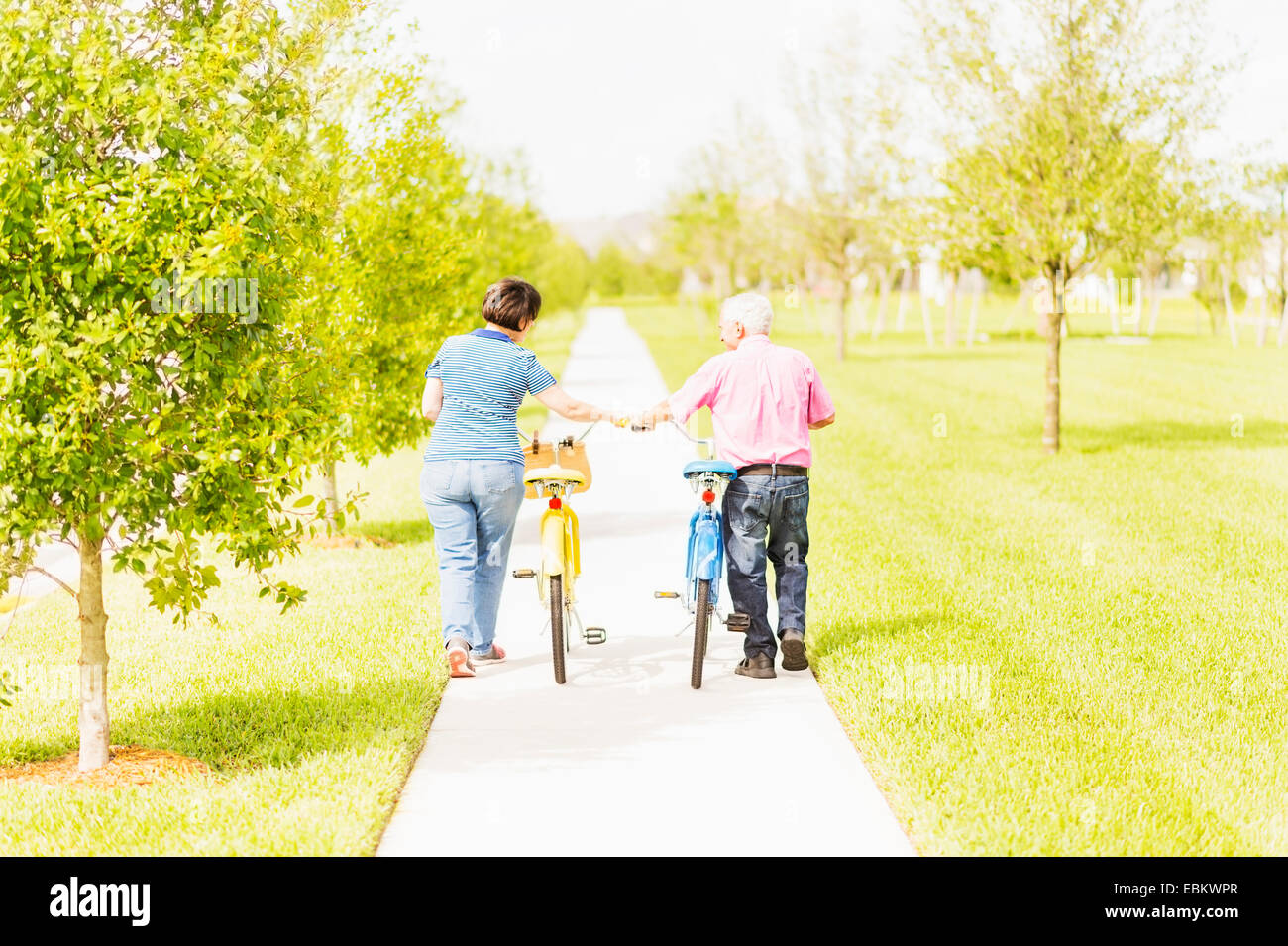 USA, Florida, Jupiter, Rear view of couple wheeling bicycles along