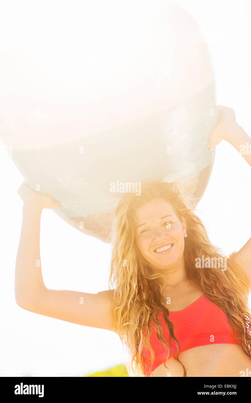 USA, Florida, Jupiter, Portrait of young woman holding surfboard over head Stock Photo