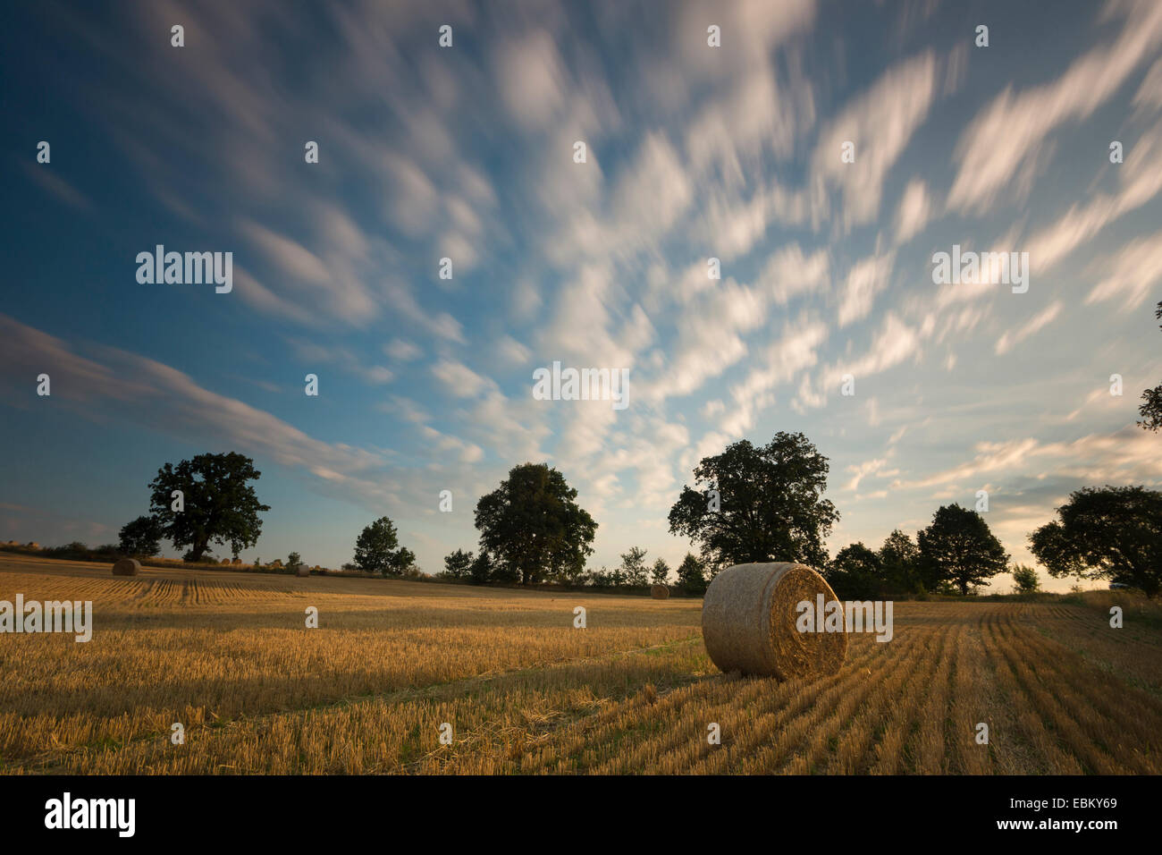 moving clouds over a stubble field with hay bales, Germany, Saxony, Vogtlaendische Schweiz Stock Photo