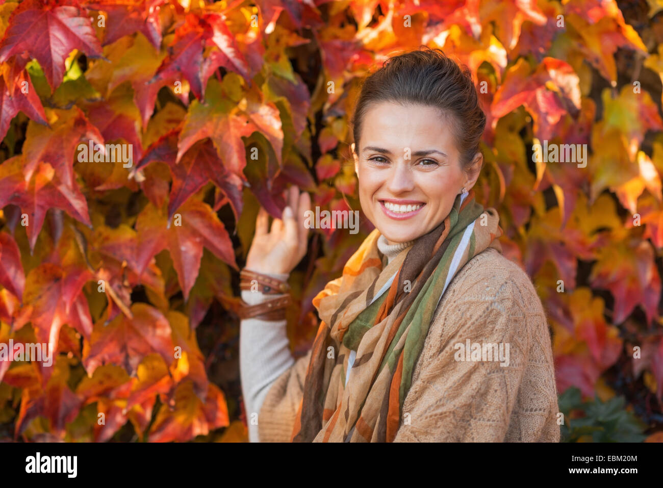 Portrait of happy young woman in front of autumn foliage Stock Photo