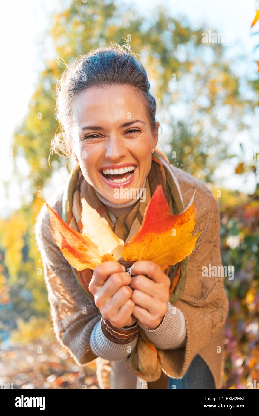 Portrait of happy young woman with autumn leafs outdoors Stock Photo