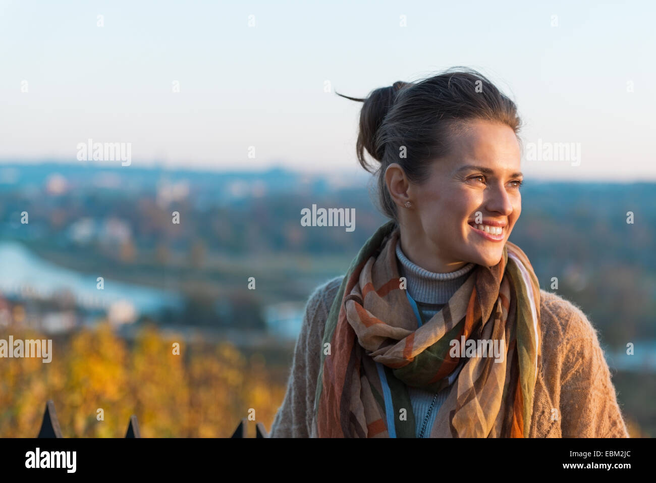 Portrait of happy young woman in autumn outdoors in evening Stock Photo