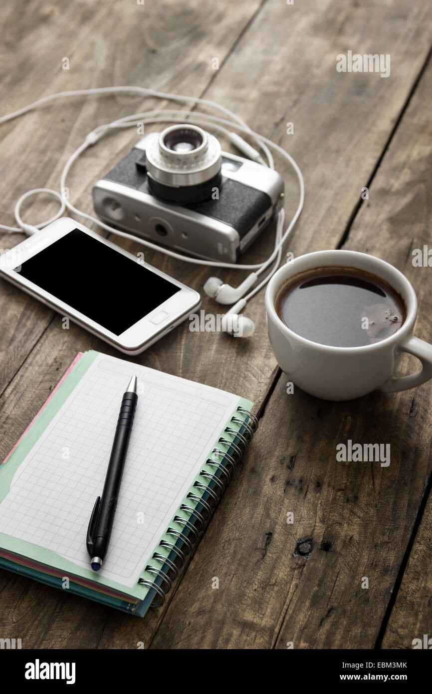 Vintage camera, diary with pan and cup pf coffee on wooden table. Stock Photo