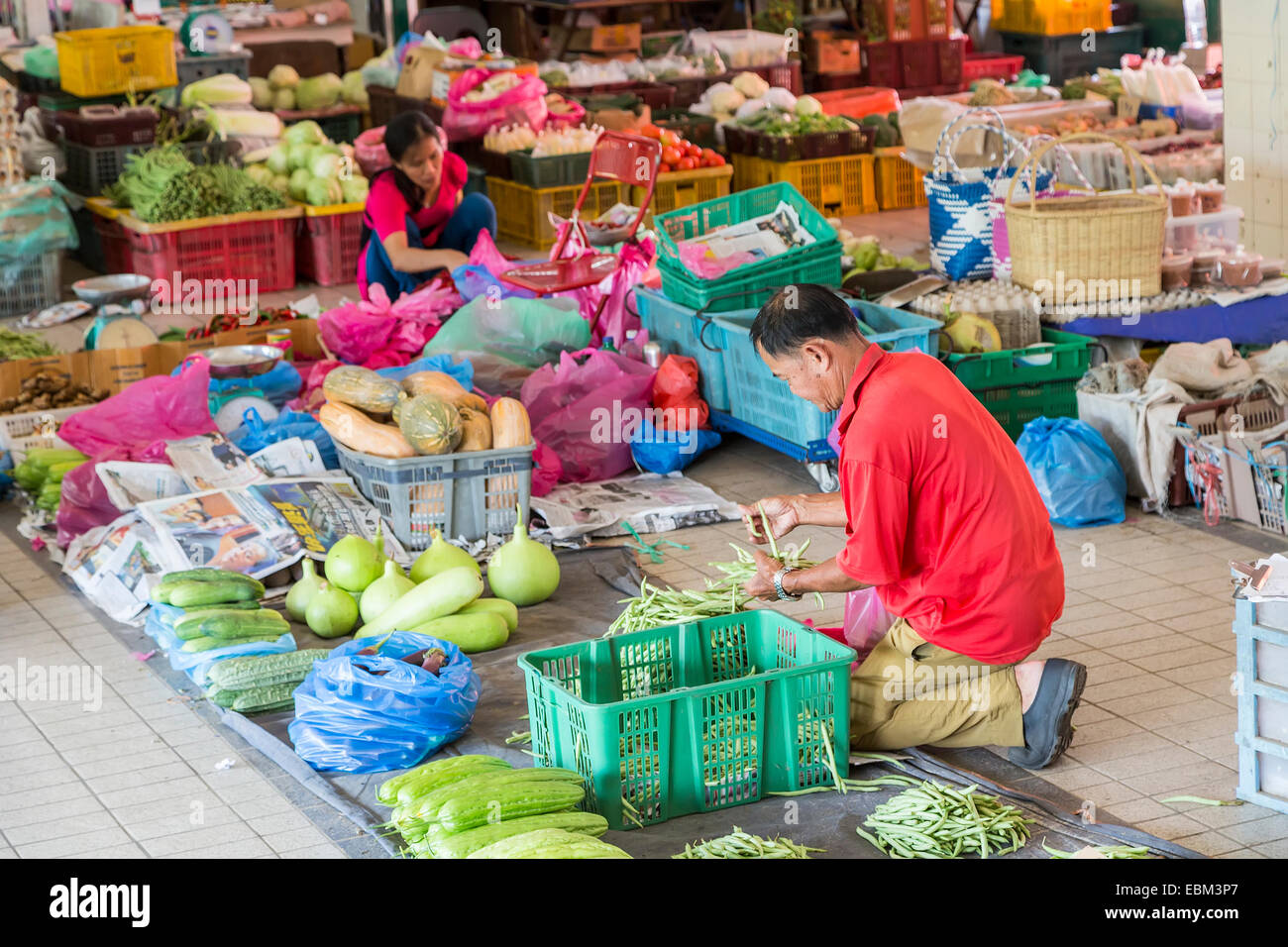 Man laying out food produce in covered market, Miri, Malaysia Stock Photo