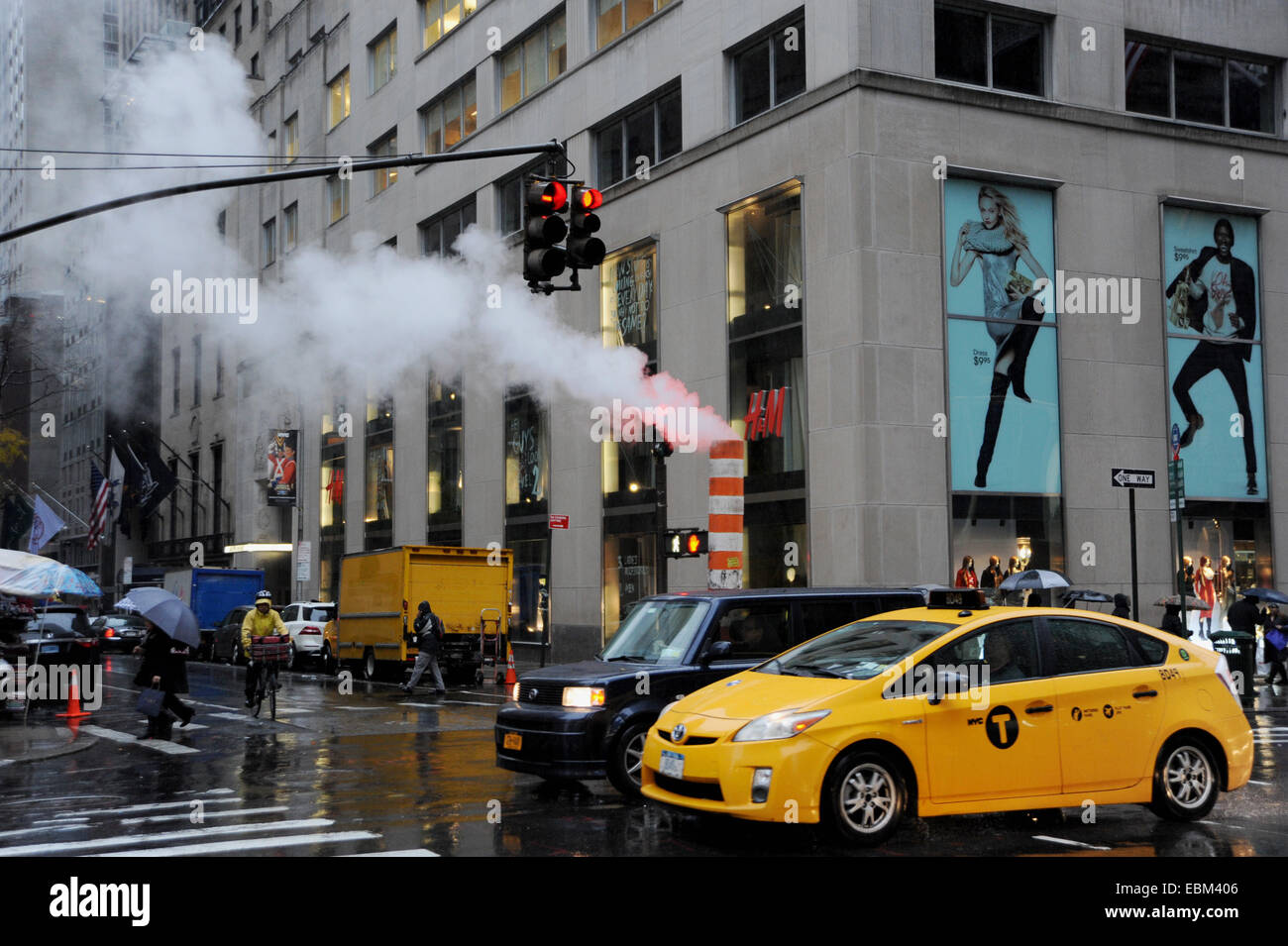 Manhattan New York USA   - Steam rises from a subway pipe in Fifth Avenue in pouring rain with yellow cab Stock Photo