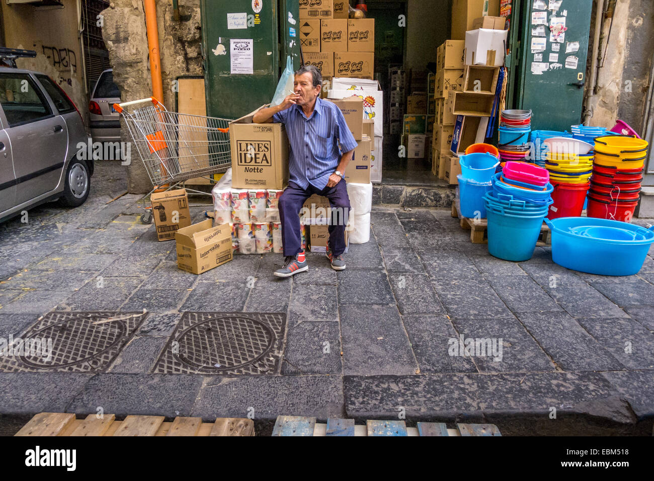 A street trader sits by his wares on the streets of Naples. Stock Photo