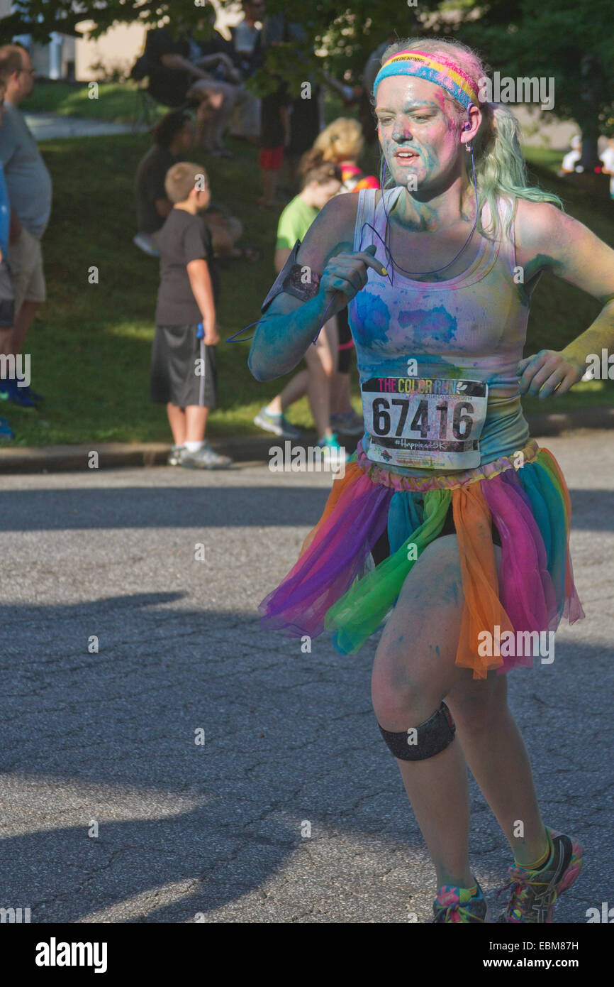 Woman runner and others splattered with colorful dye race in the the happy Asheville 5K Color Run Stock Photo