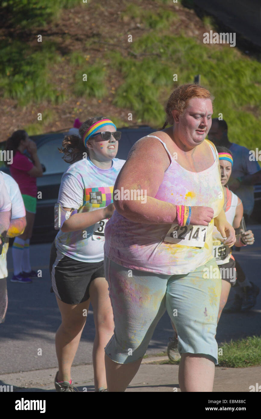 Woman runners in clothing splattered with colorful dye race in the the happy Asheville 5K Color Run Stock Photo