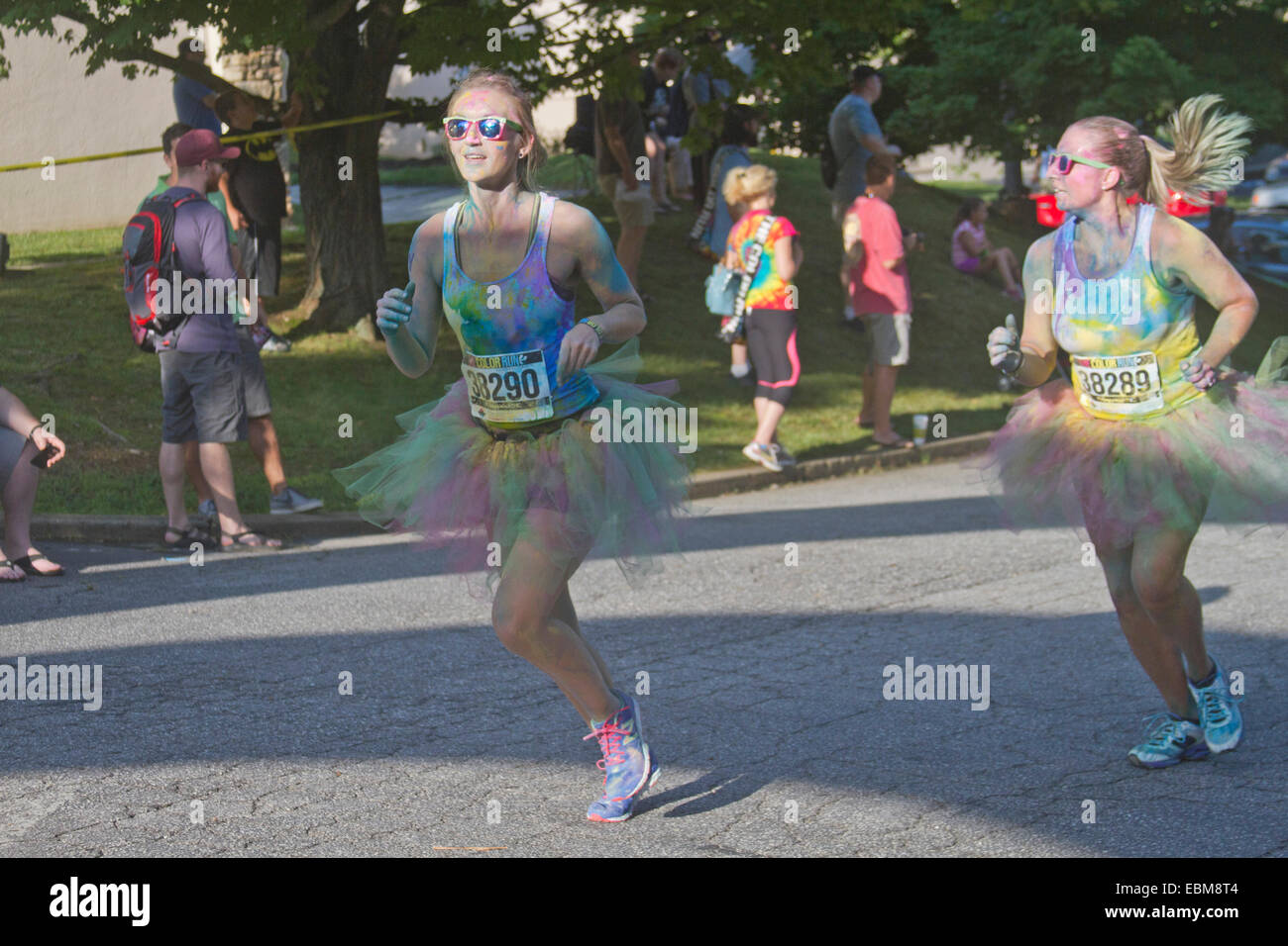 Runners splattered with colorful dye race in the the happy Asheville 5K Color Run in summer Stock Photo